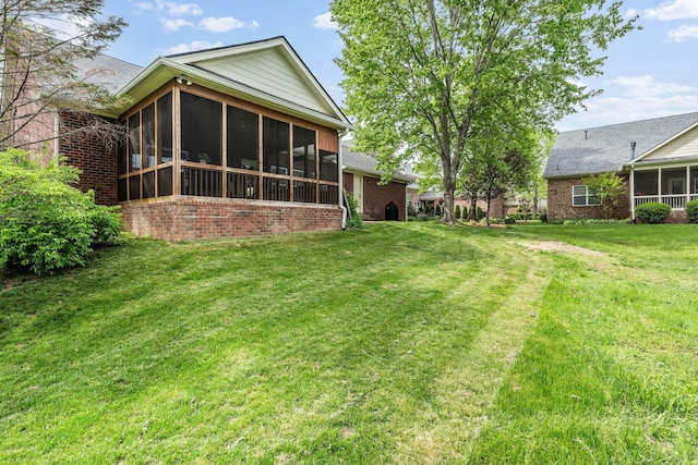 rear view of house featuring a lawn, a sunroom, and brick siding