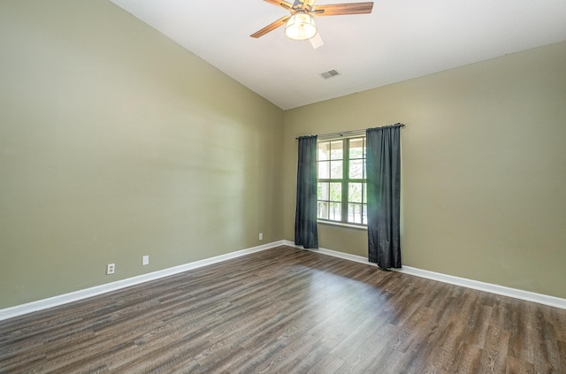 spare room featuring visible vents, dark wood-style flooring, lofted ceiling, baseboards, and a ceiling fan