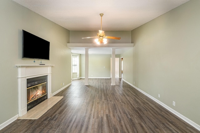 unfurnished living room with a glass covered fireplace, baseboards, a ceiling fan, and dark wood finished floors