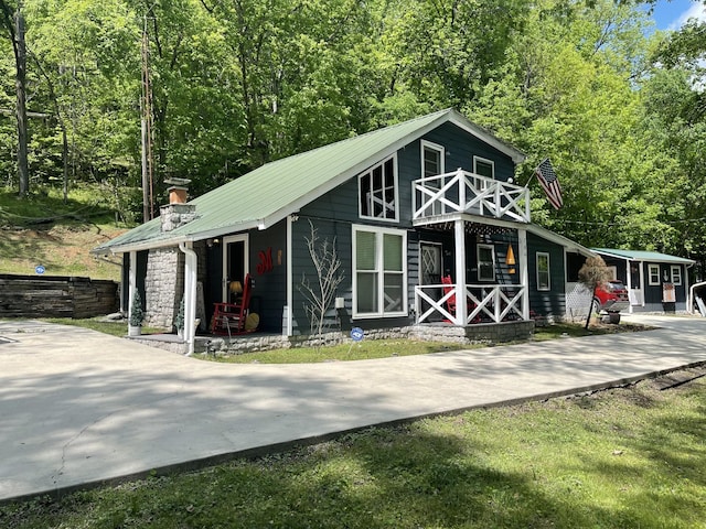 view of outdoor structure featuring a view of trees, covered porch, and concrete driveway