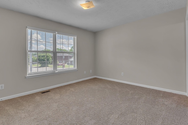 unfurnished room with carpet floors, a textured ceiling, baseboards, and visible vents