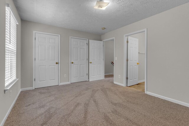 unfurnished bedroom with carpet floors, baseboards, and a textured ceiling