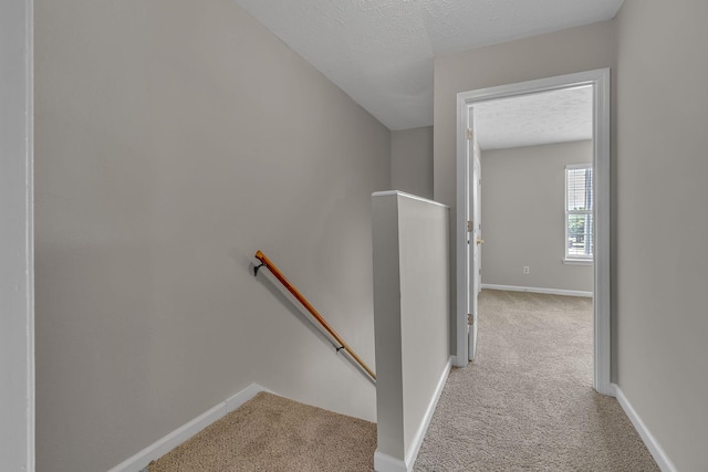 stairway with baseboards, carpet flooring, and a textured ceiling