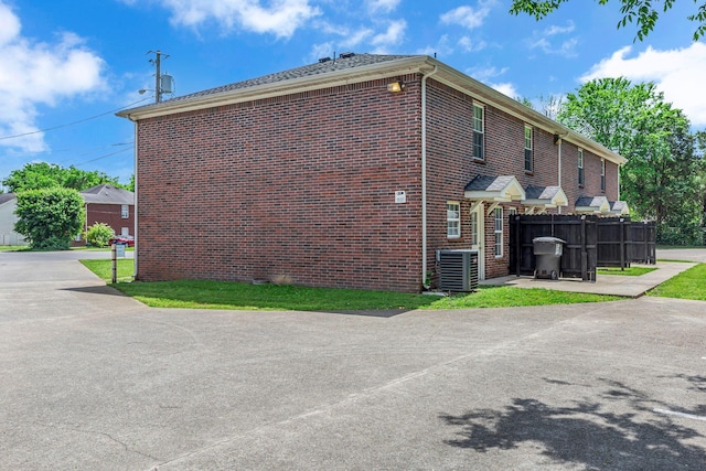 view of home's exterior featuring central air condition unit, fence, and brick siding