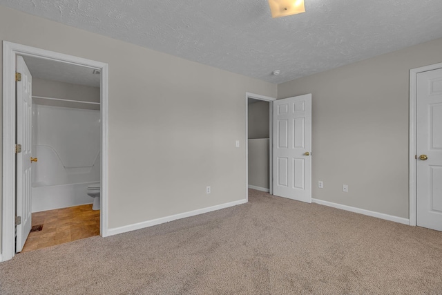 unfurnished bedroom with baseboards, a textured ceiling, and carpet