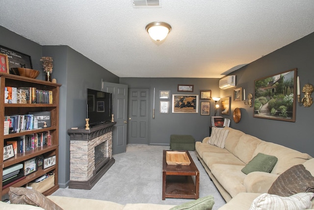 carpeted living area with a textured ceiling, visible vents, a stone fireplace, and a wall mounted air conditioner