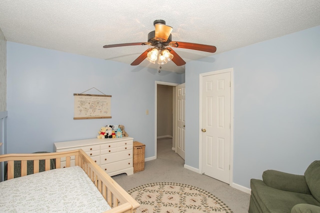 bedroom with baseboards, a ceiling fan, a textured ceiling, and light carpet