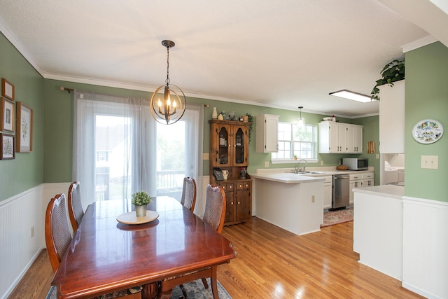 dining room featuring light wood-style floors, ornamental molding, wainscoting, and a notable chandelier