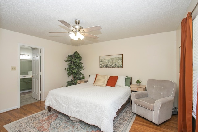 bedroom featuring a textured ceiling, ensuite bathroom, a ceiling fan, and wood finished floors