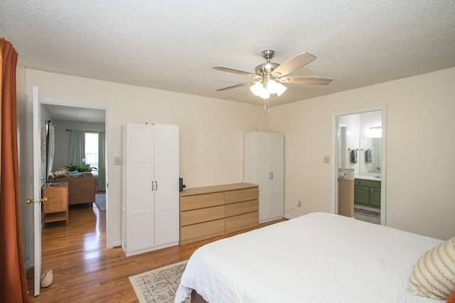 bedroom featuring connected bathroom, a textured ceiling, ceiling fan, and wood finished floors