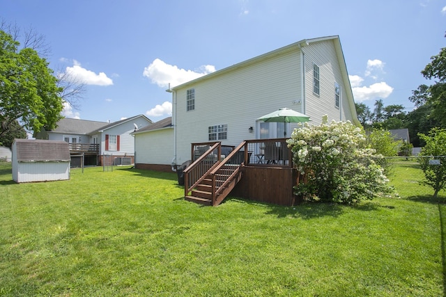 back of property featuring fence, a storage unit, a deck, an outdoor structure, and a yard