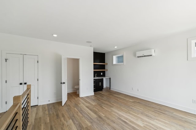 interior space with light wood-style floors, baseboards, recessed lighting, and a wall mounted air conditioner