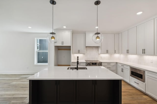 kitchen with light countertops, white cabinetry, appliances with stainless steel finishes, and a sink