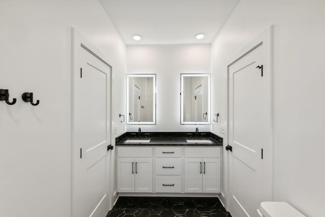 bathroom with double vanity, toilet, a sink, and marble finish floor