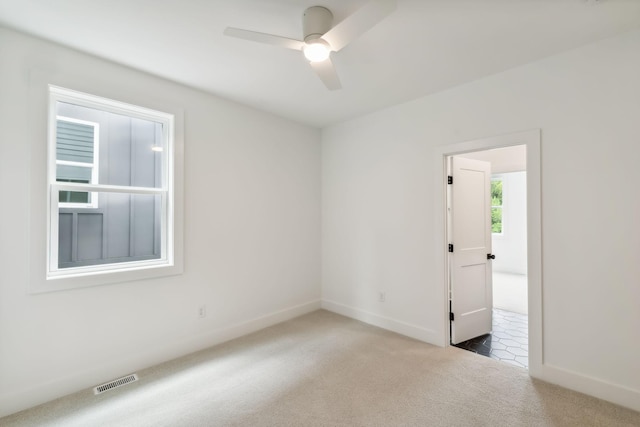 carpeted spare room featuring baseboards, ceiling fan, and visible vents
