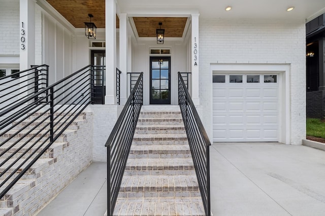 doorway to property with brick siding, an attached garage, driveway, and covered porch