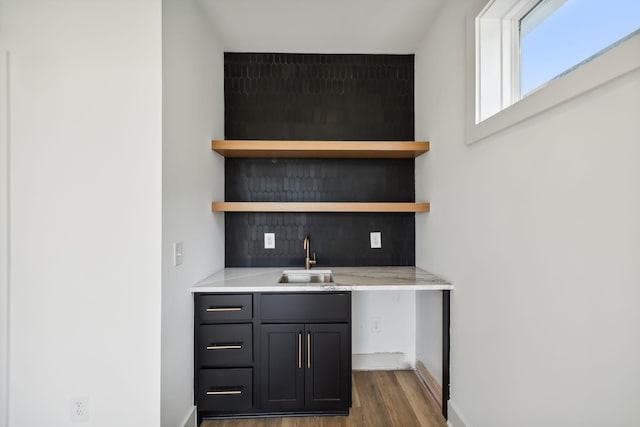 bar featuring indoor wet bar, a sink, baseboards, and wood finished floors