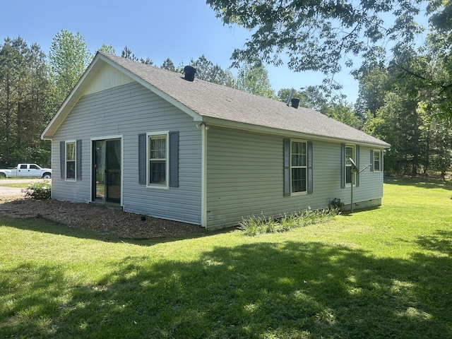 rear view of house featuring a lawn and roof with shingles