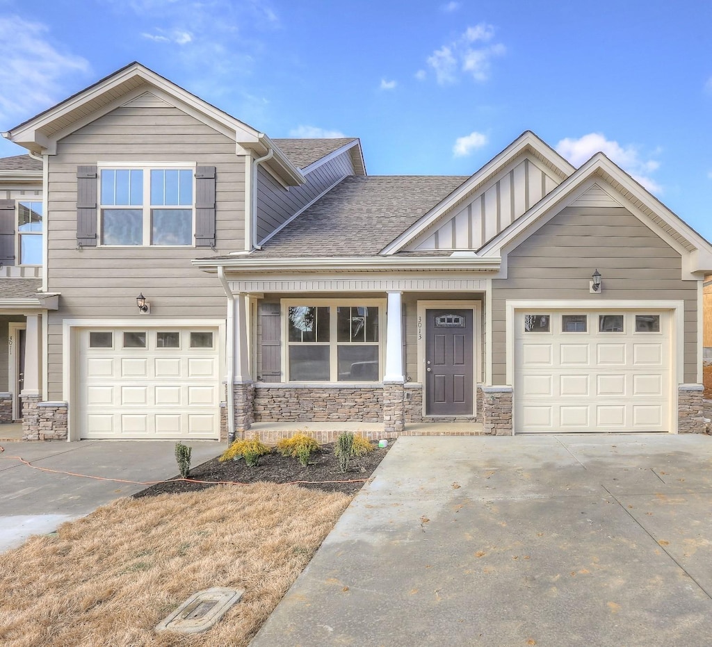 view of front facade with concrete driveway, board and batten siding, and stone siding