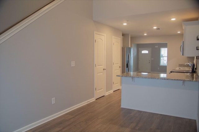 319 Mattie Ln, Spring Hill, TN 37174 - kitchen featuring a breakfast bar area, appliances with stainless steel finishes, a peninsula, dark wood-style floors, and stone counters