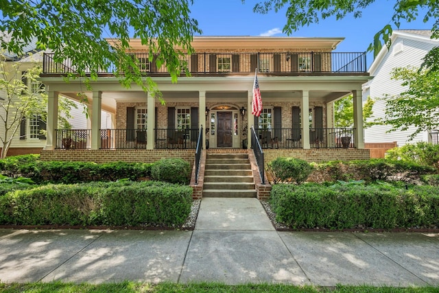 view of front of property featuring covered porch, brick siding, and a balcony