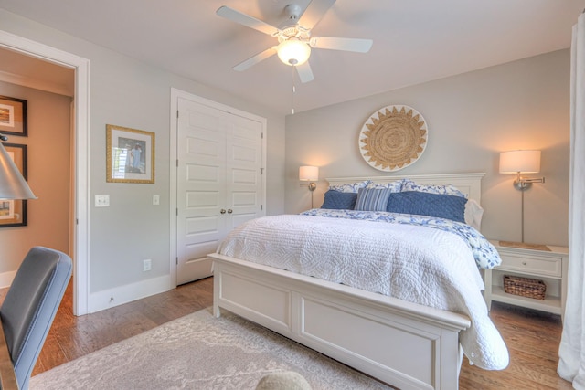 bedroom with a closet, a ceiling fan, baseboards, and wood finished floors