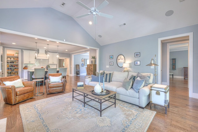 living room featuring ceiling fan, visible vents, light wood finished floors, and high vaulted ceiling