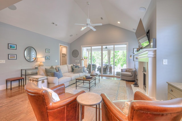 living area featuring visible vents, ceiling fan, high vaulted ceiling, a fireplace with flush hearth, and light wood finished floors