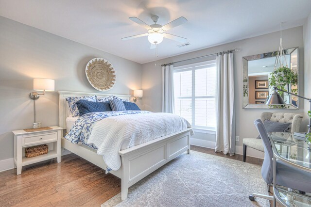 bedroom featuring visible vents, baseboards, ceiling fan, and wood finished floors