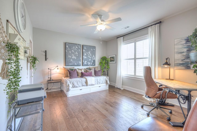 home office with ceiling fan, visible vents, baseboards, and hardwood / wood-style floors
