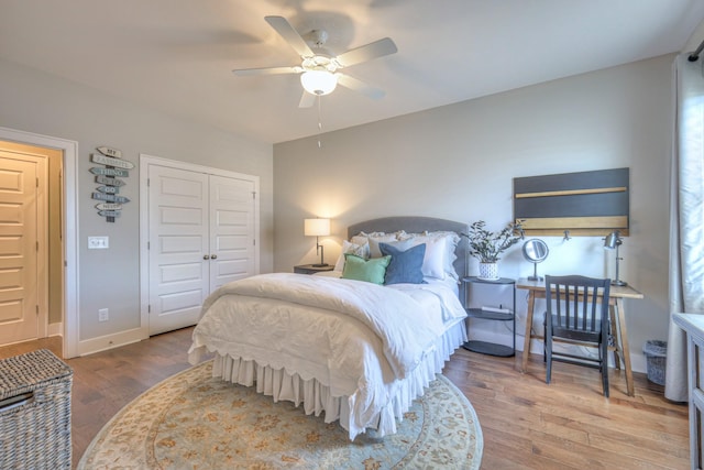 bedroom with baseboards, ceiling fan, wood finished floors, and a closet
