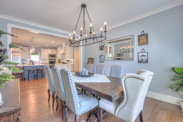 dining area featuring crown molding, baseboards, an inviting chandelier, and wood finished floors