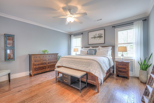 bedroom with ceiling fan, baseboards, light wood-type flooring, visible vents, and ornamental molding