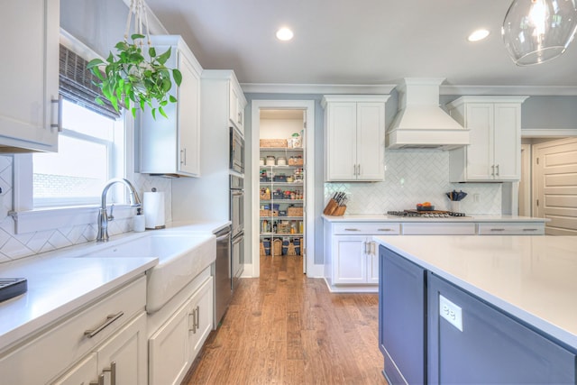 kitchen with custom range hood, light countertops, white cabinetry, and light wood finished floors