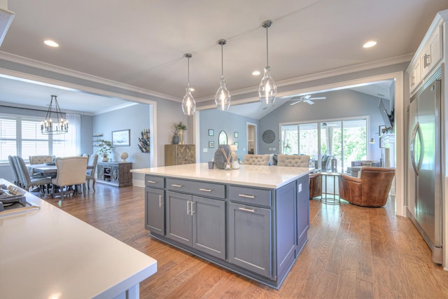 kitchen featuring wood finished floors, open floor plan, light countertops, built in fridge, and ceiling fan with notable chandelier
