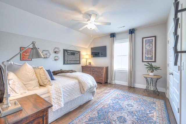 bedroom with visible vents, wood finished floors, baseboards, ceiling fan, and vaulted ceiling