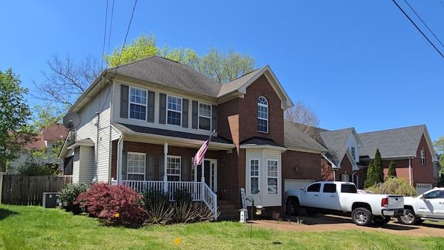 traditional-style home with a garage, fence, covered porch, a front yard, and brick siding
