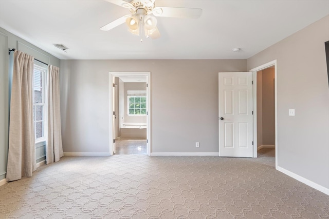 carpeted spare room featuring baseboards, ceiling fan, and visible vents