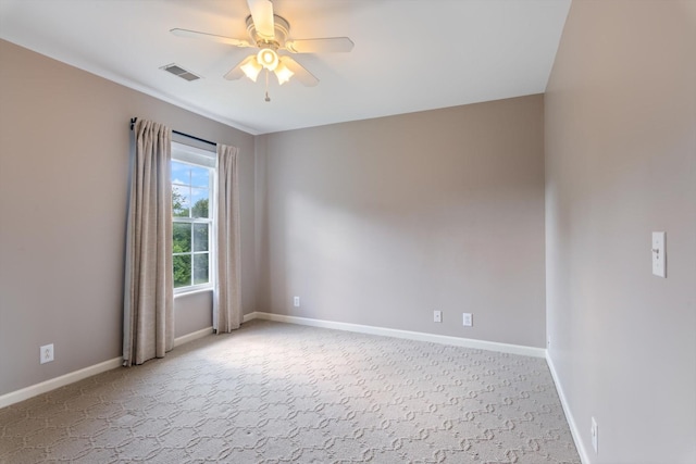 empty room with baseboards, ceiling fan, visible vents, and light colored carpet