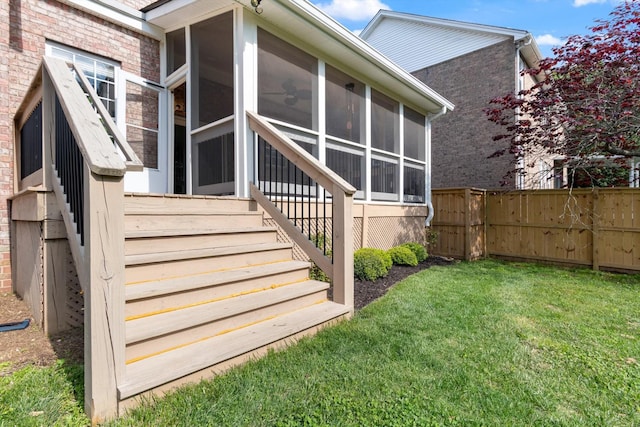 doorway to property with a lawn, brick siding, and fence