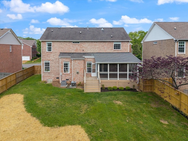back of property featuring central air condition unit, brick siding, a sunroom, a fenced backyard, and a lawn