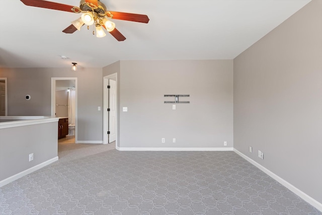 unfurnished room with a ceiling fan, baseboards, and carpet