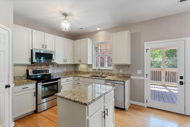 kitchen featuring a sink, light wood finished floors, appliances with stainless steel finishes, and light stone countertops