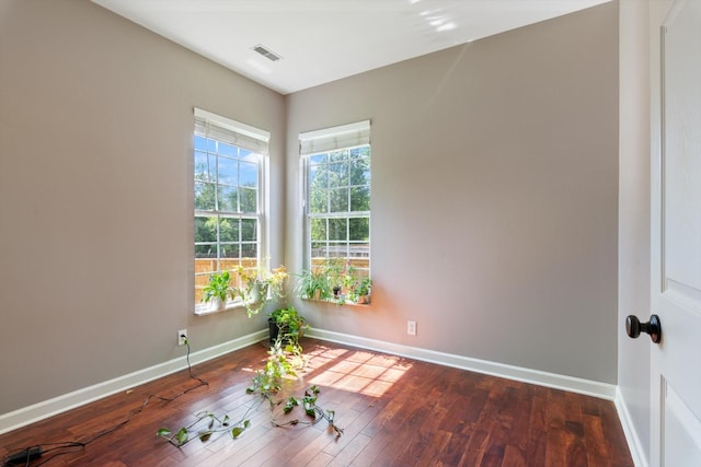 spare room featuring visible vents, baseboards, and hardwood / wood-style floors