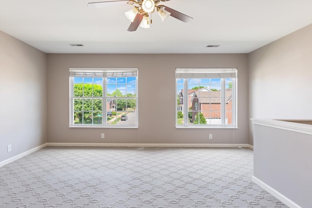spare room with a healthy amount of sunlight, carpet flooring, and visible vents