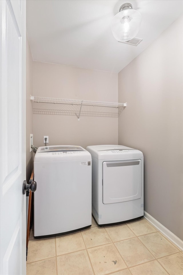 washroom featuring light tile patterned flooring, laundry area, baseboards, visible vents, and washing machine and dryer