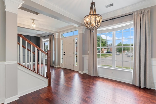 foyer entrance featuring a notable chandelier, stairs, wood finished floors, visible vents, and ornamental molding