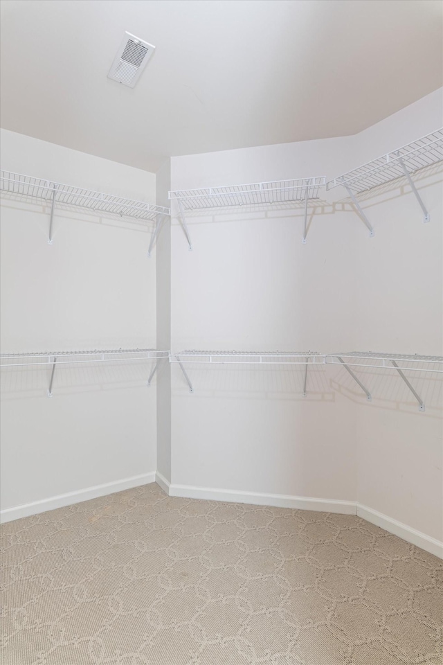 walk in closet featuring visible vents and light colored carpet