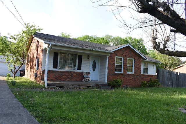 view of front facade featuring brick siding, a front lawn, fence, and a porch