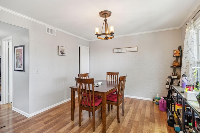 dining area with visible vents, crown molding, wood finished floors, baseboards, and a notable chandelier